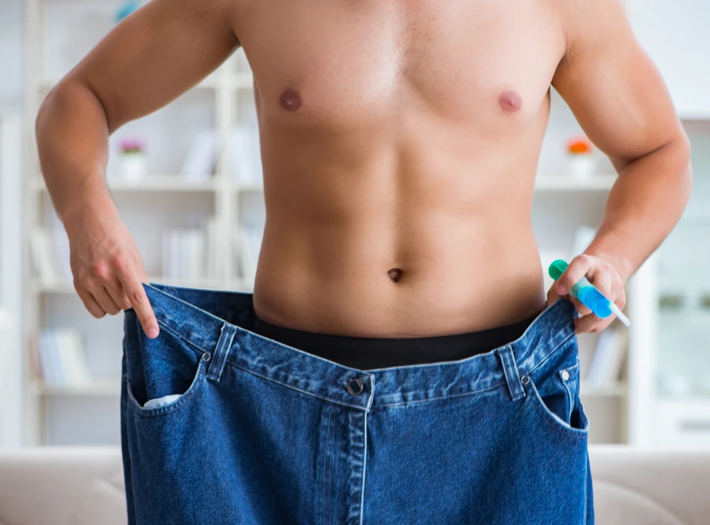 Man showing weight loss progress in loose jeans